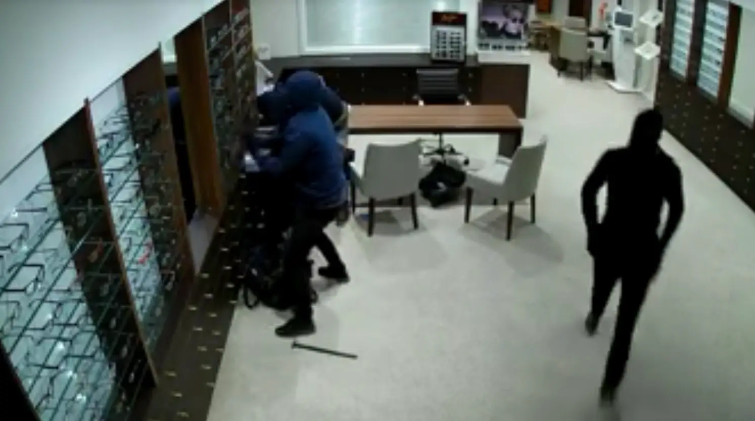 The masked men enter the Draybank Road shop - a weapon can be seen on the floor